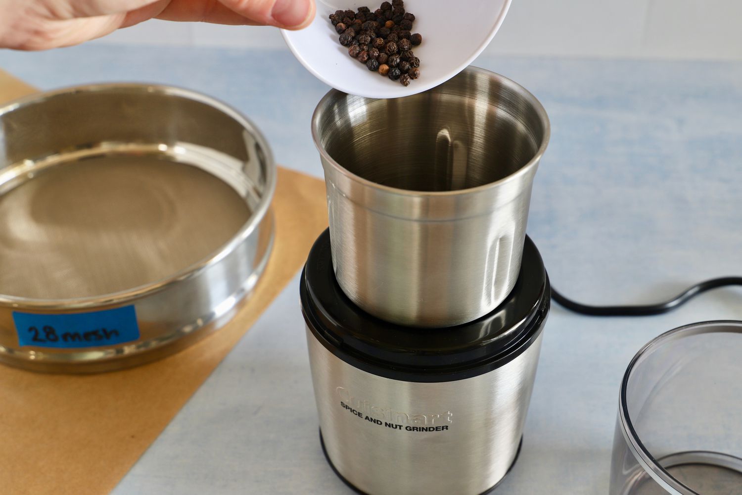person pouring peppercorns into the cuisinart spice grinder