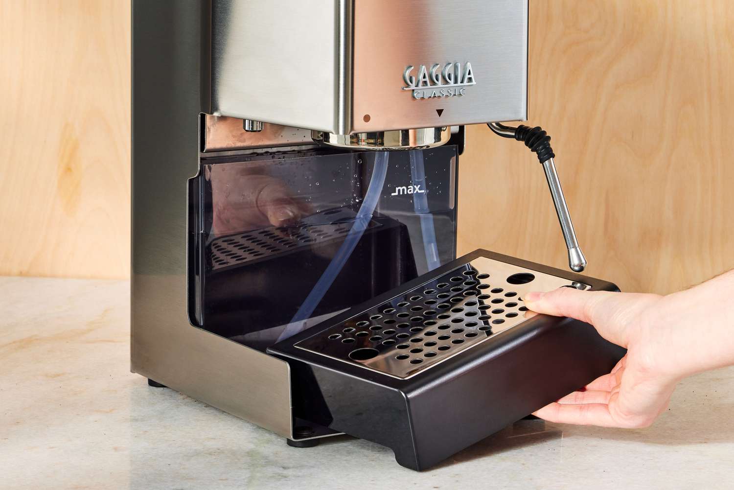 Hand adjusting the tray of the Gaggia Classic Pro Espresso Machine on a counter 
