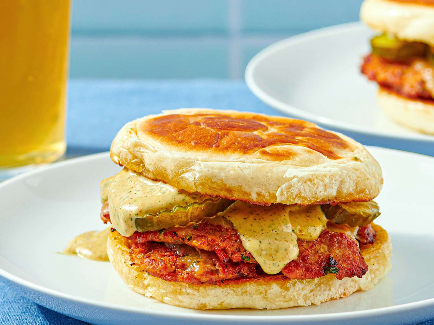 Turkey chourico smash burger on a plate with pickles and sauce between buns