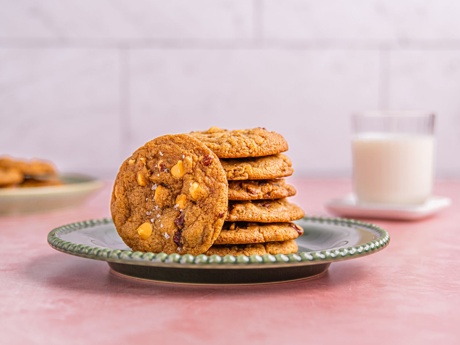 A plate of cookies with visible nuts, with a glass of milk in the background