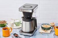 OXO Brew 8-Cup Coffee Maker displayed on a kitchen counter with breakfast food and mug of coffee
