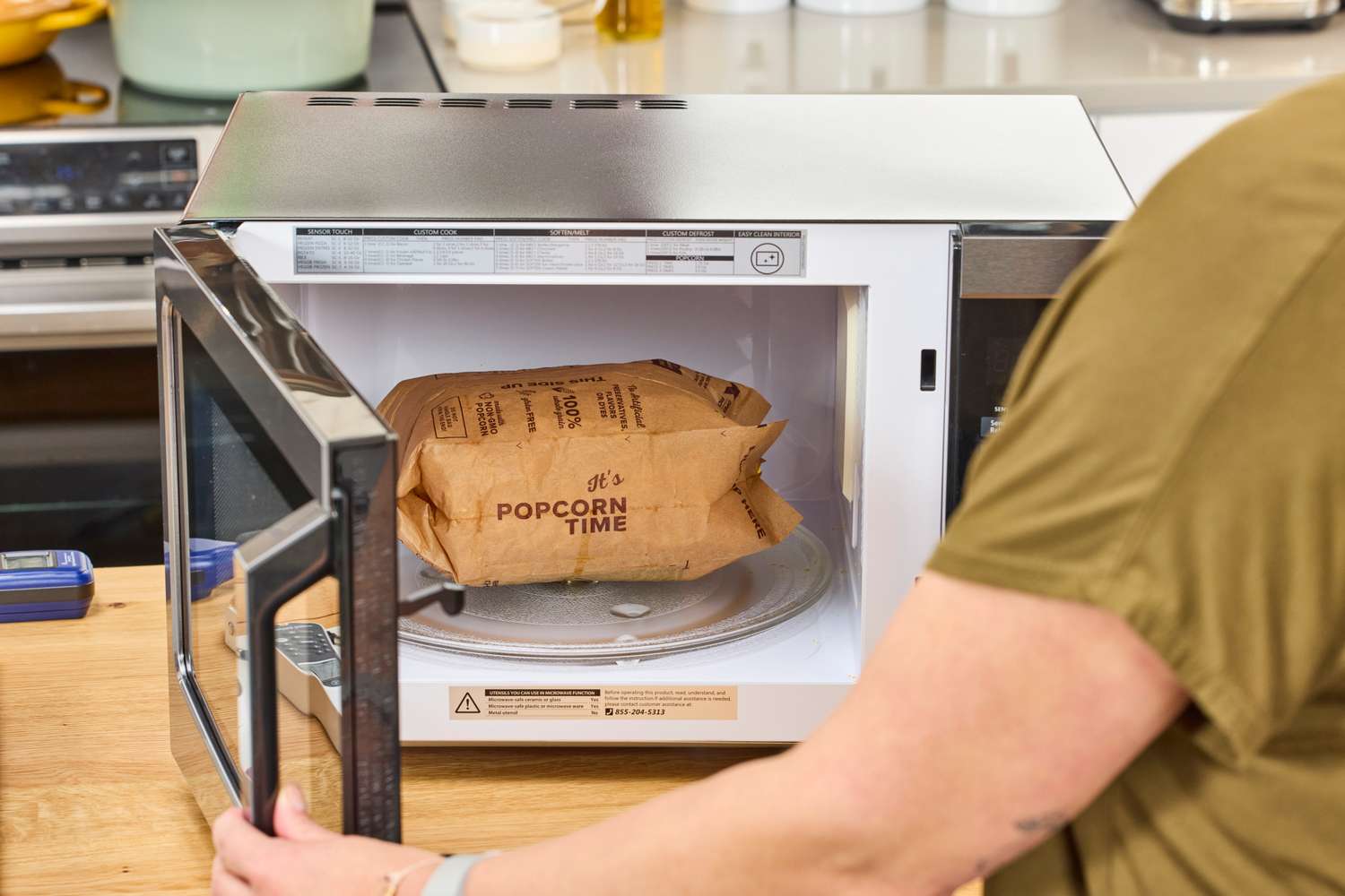 A person looking at a popped bag of popcorn in the Toshiba EM131A5C-BS Microwave Oven