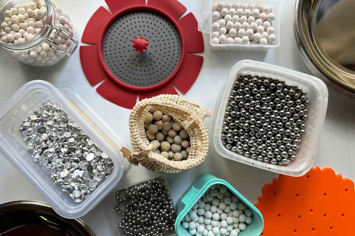 A collection of different styles of pie weights in storage boxes and bags.