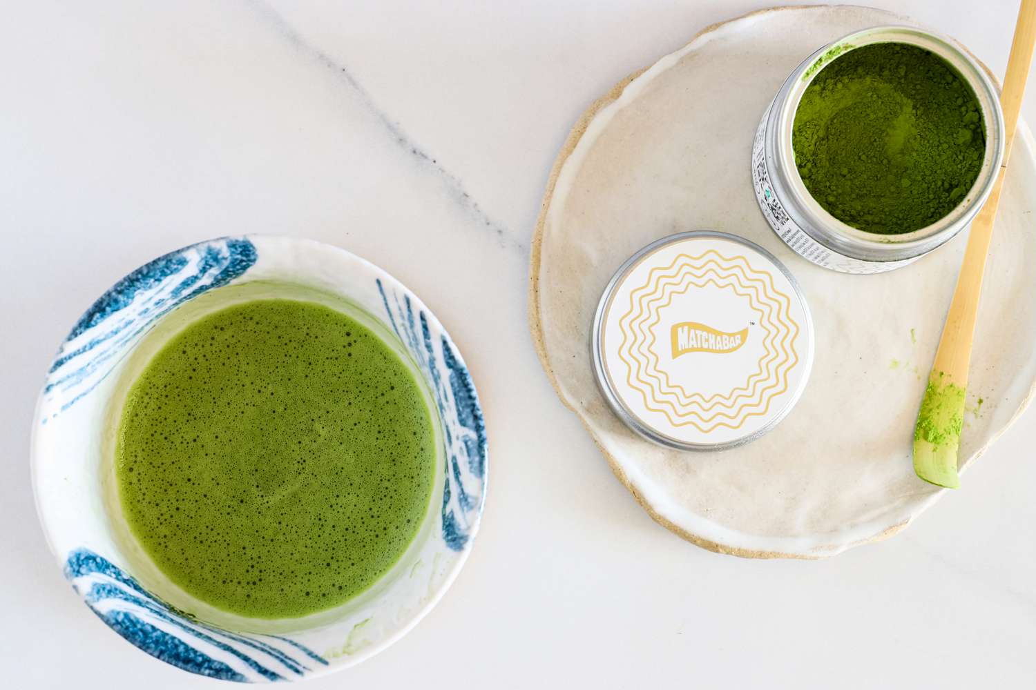 An overhead shot of a glass of Matcha Bar Premium Blend next to the container