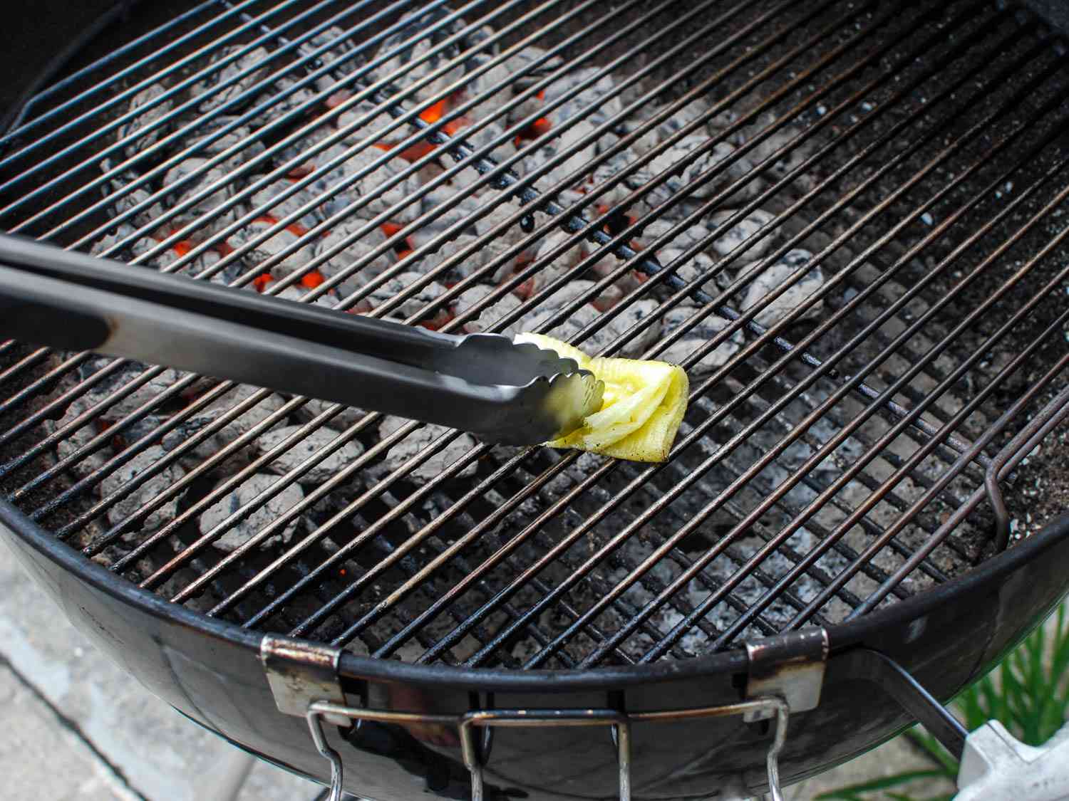 Oiling the grill grate with a towel and tongs