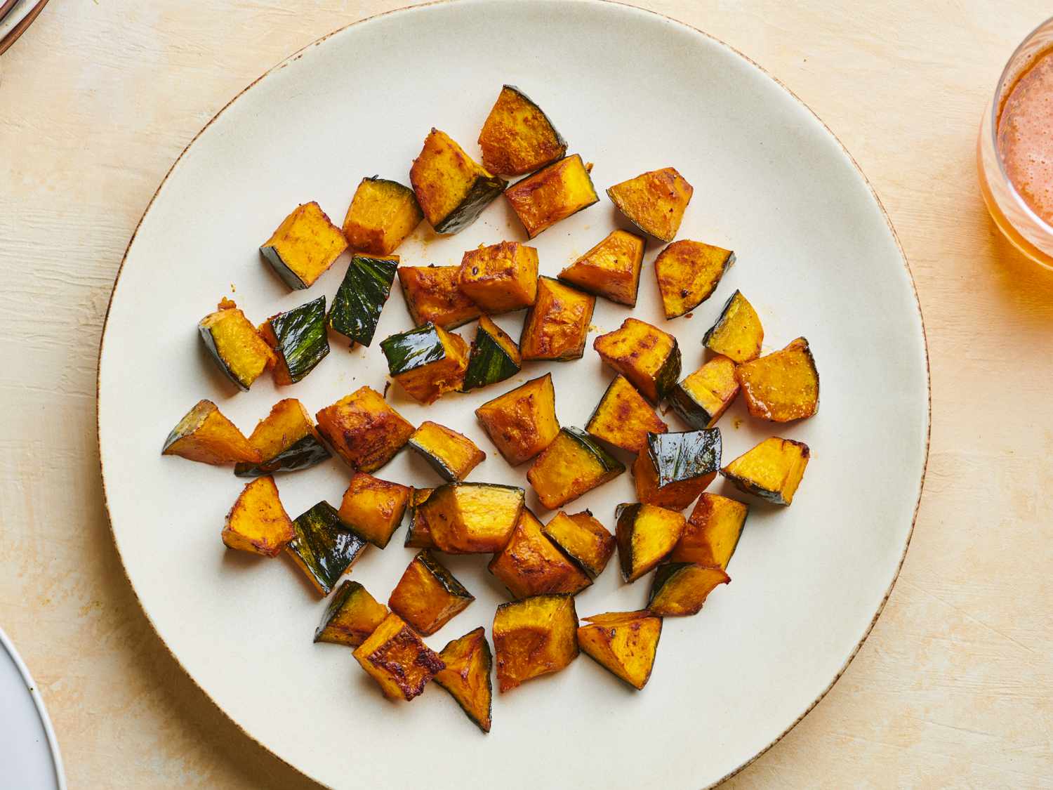 Roasted kabocha squash with soy sauce, butter, and shichimi togarashi on a white ceramic plate.