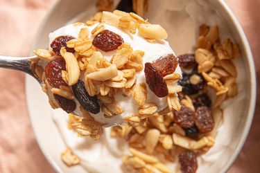 Overhead view a of spoon lifting up granola and yogurt