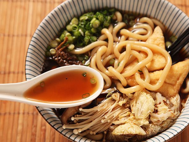 A spoonful of umami-rich broth from a bowl of vegan udon with mushrooms 