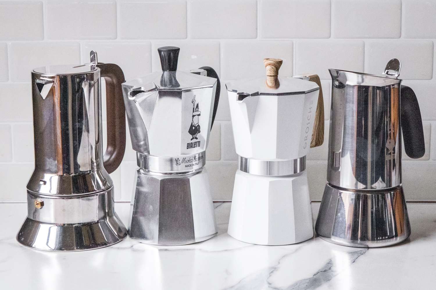 Four moka pots lined up on a kitchen counter