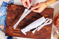 a person holding two blades from an electric knife