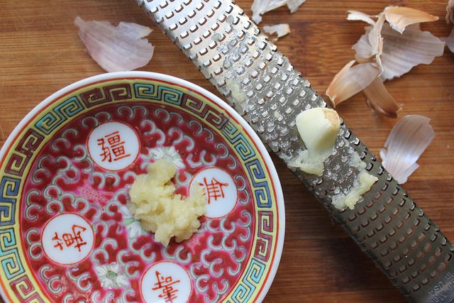 Peeled garlic cloves are microplaned into a small bowl for garnishing the Taiwanese danzai noodle soup.
