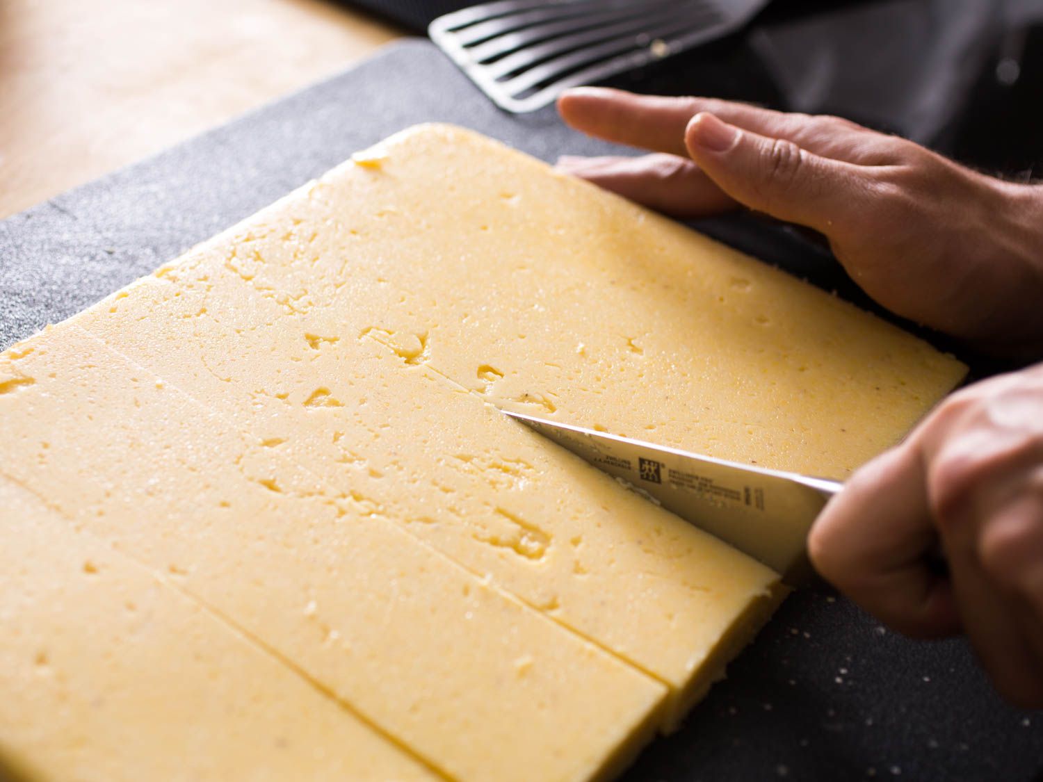 Slicing cold polenta with a knife.