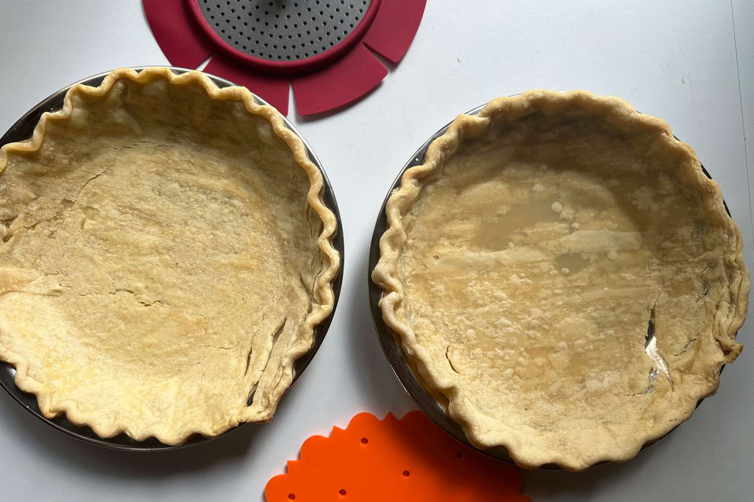 Two cracked pie shells on a white surface.