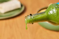 Person pouring El Yucateco Salsa Picante Verde De Chile Habañero