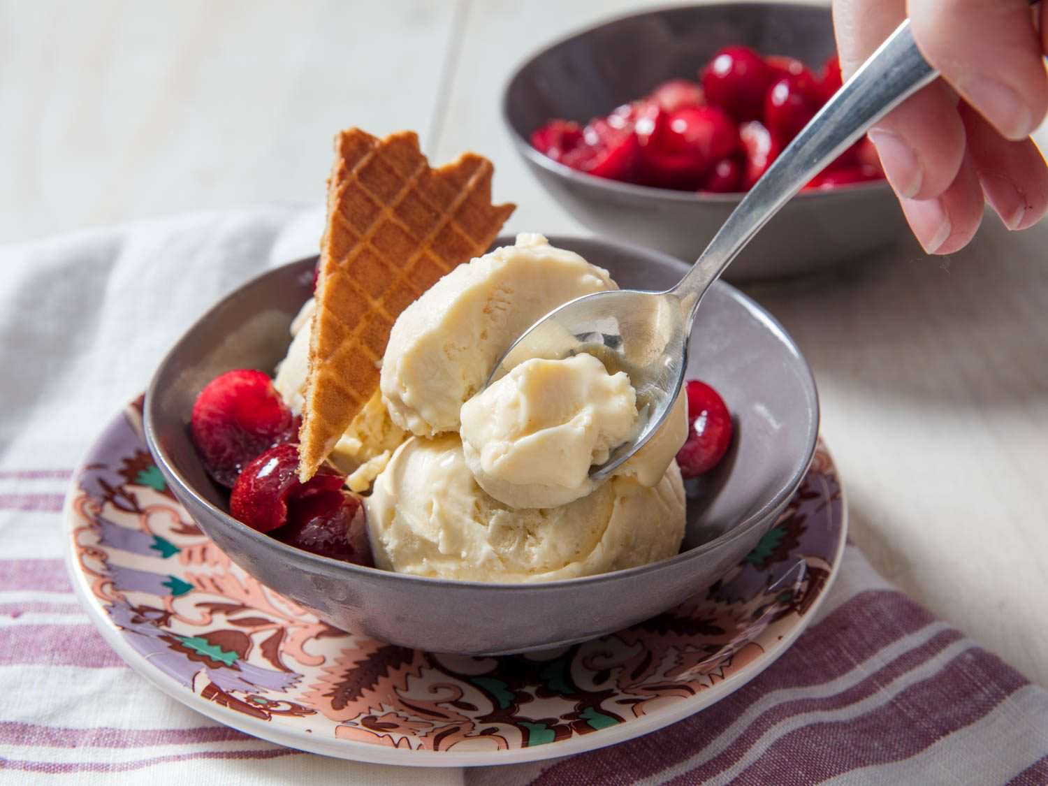 A two-scoop bowl of mascarpone ice cream. A spoon is carving off a bite.