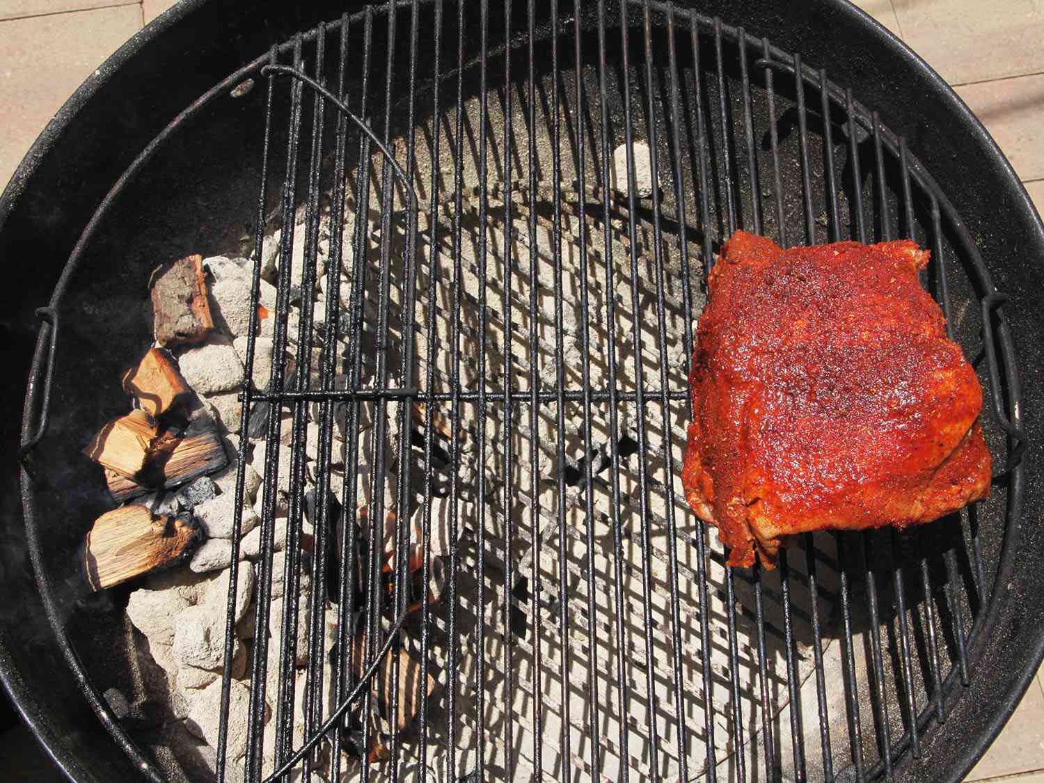 pork shoulder being cooked on a grill over indirect heat