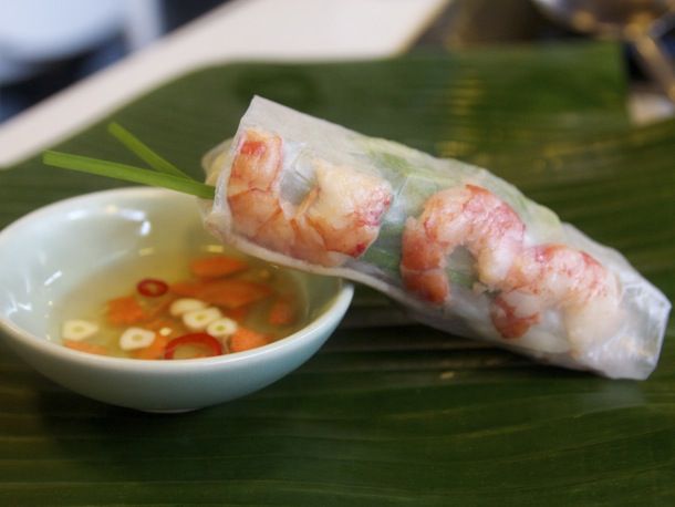 A Gỏi cuốn (Spring Roll) leaning on a small bowl with dipping sauce inside 