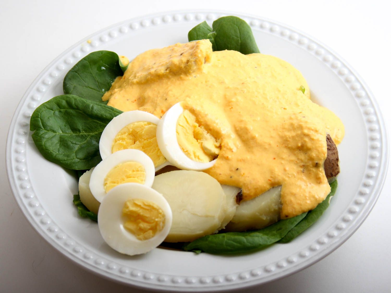 A plate of Peruvian papas huancaina with leaves and halved boiled eggs.