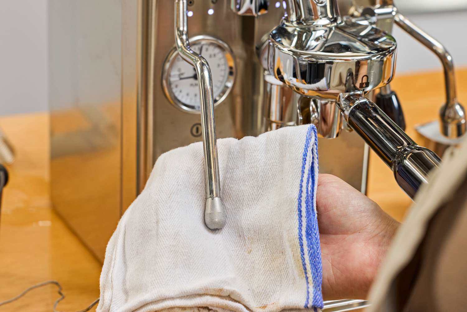 A hand using a cloth to wipe part of the Lelit MaraX Espresso Machine PL62X-120