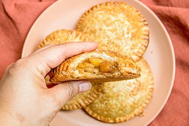 Overhead view of a hand holding an apple hand pie with a bite taken out of it 
