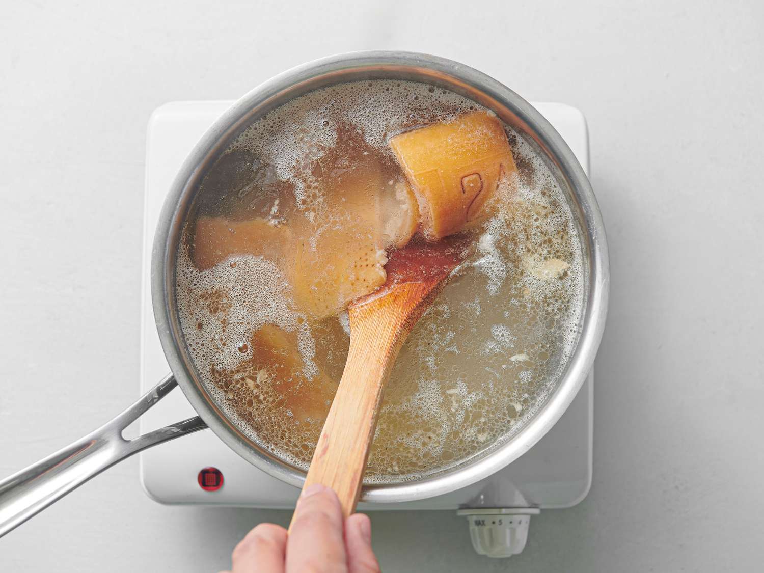 Parmesan rinds, water, and salt maintaining a gentle simmer inside 3-quart saucier
