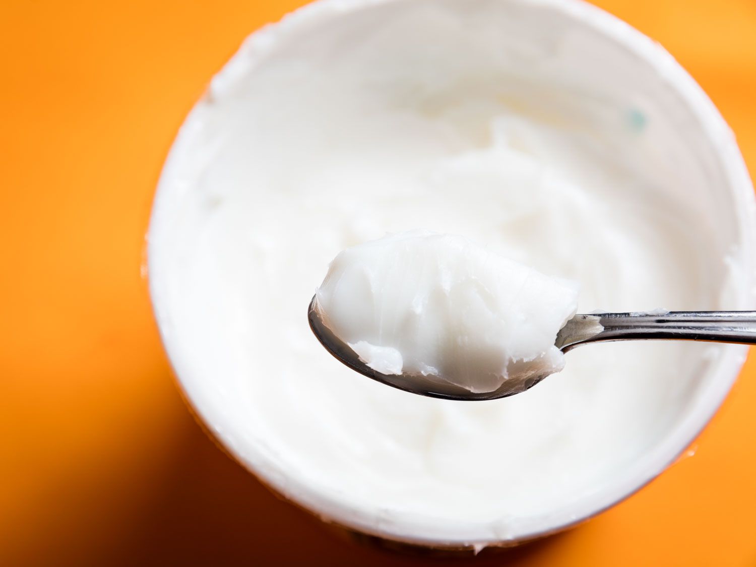 Close-up of a spoonful of white lard being lifted from a container of lard