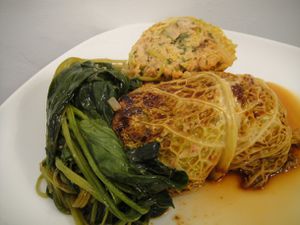 Asian Cabbage Rolls with Spicy Pork on a plate with sauce and greens. 