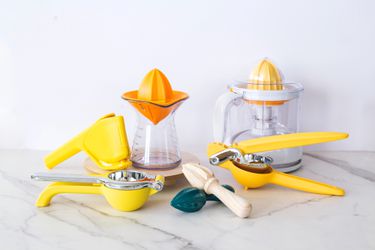 Various citrus juicers on a marble countertop. 