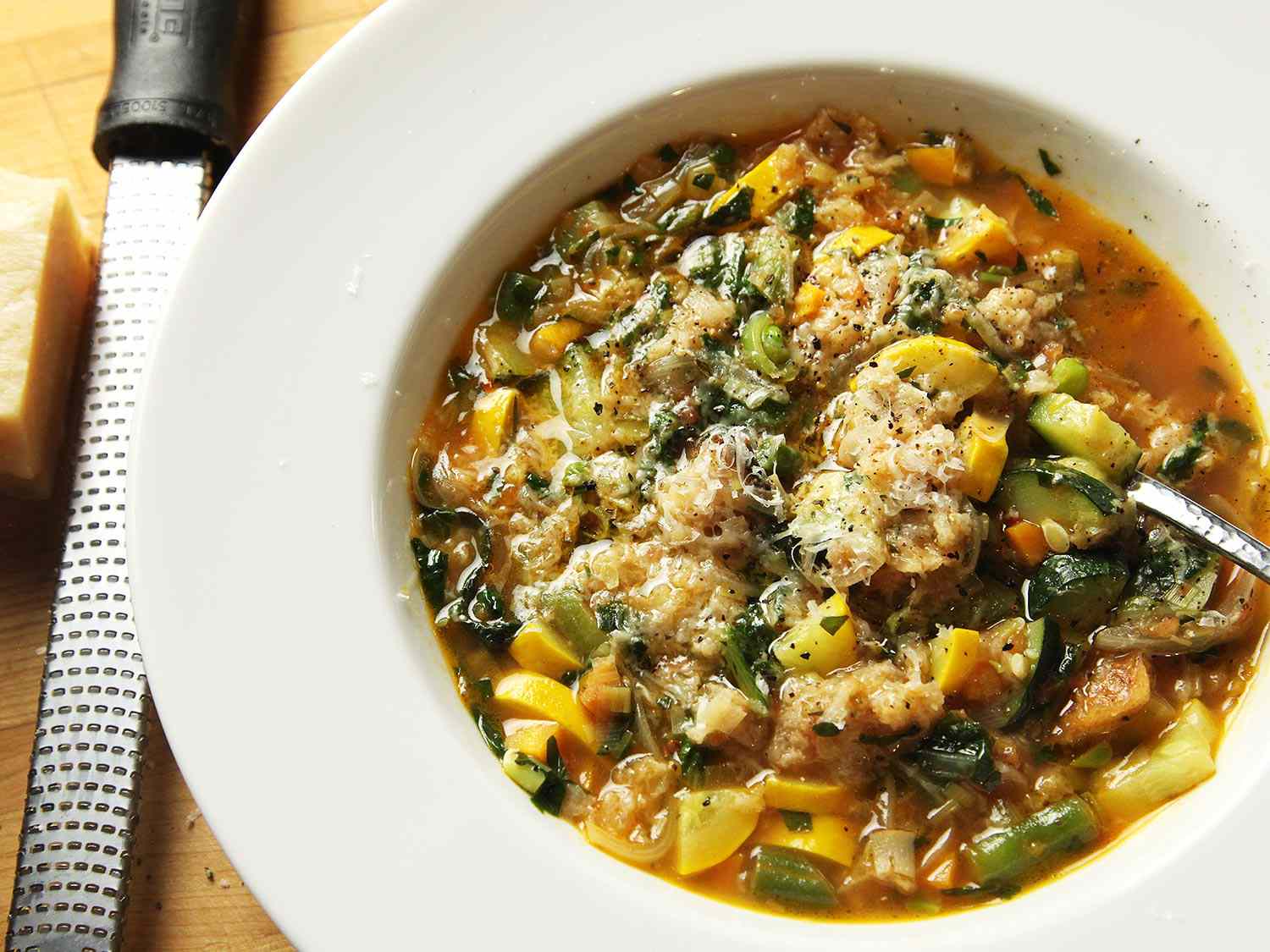 A bowl of ribollita made with summer vegetables, showered with Parmesan and black pepper.