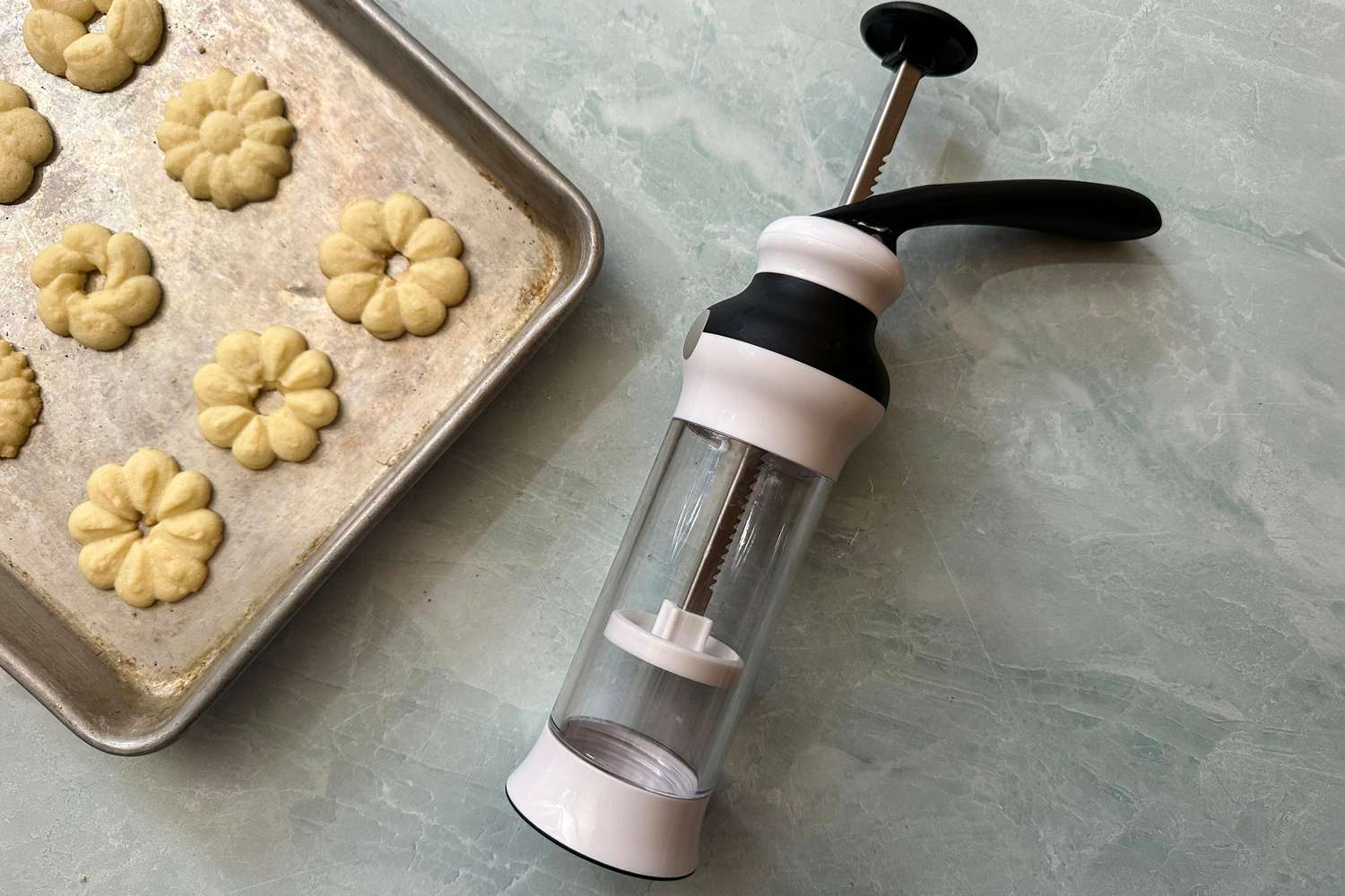 The OXO Good Grips Cookie Press next to a tray of cookies