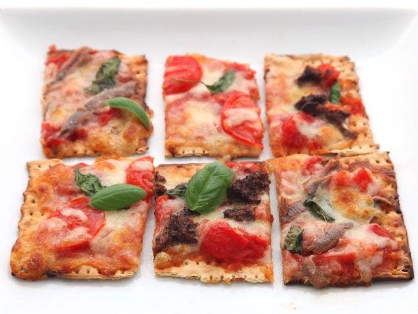 Squares of matzo pizza on a white surface.