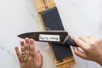 A person sharpening a knife on a whetstone