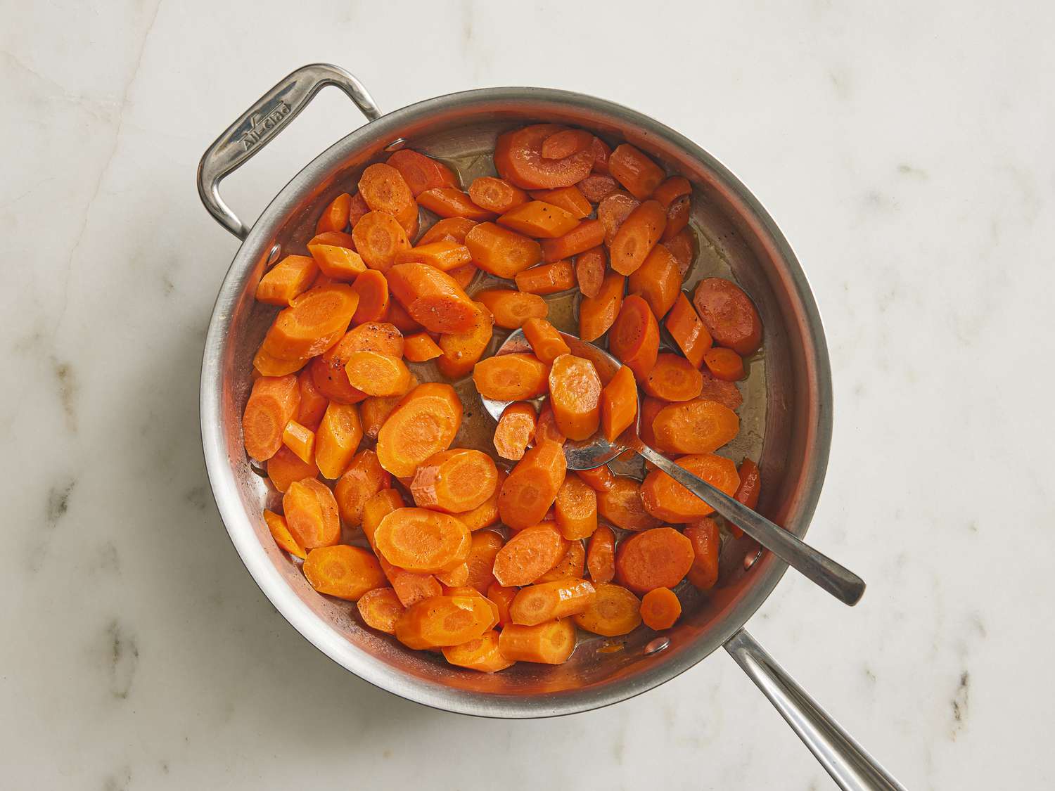 Vinegar added into carrot pan with a spoon 