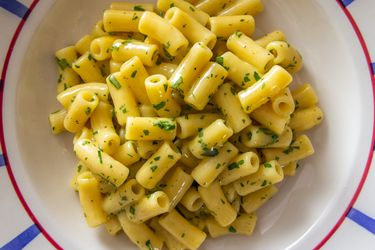 Pasta cacio e uova (Neapolitan pasta with eggs and cheese) on a white platter, garnished with fresh parsley. 