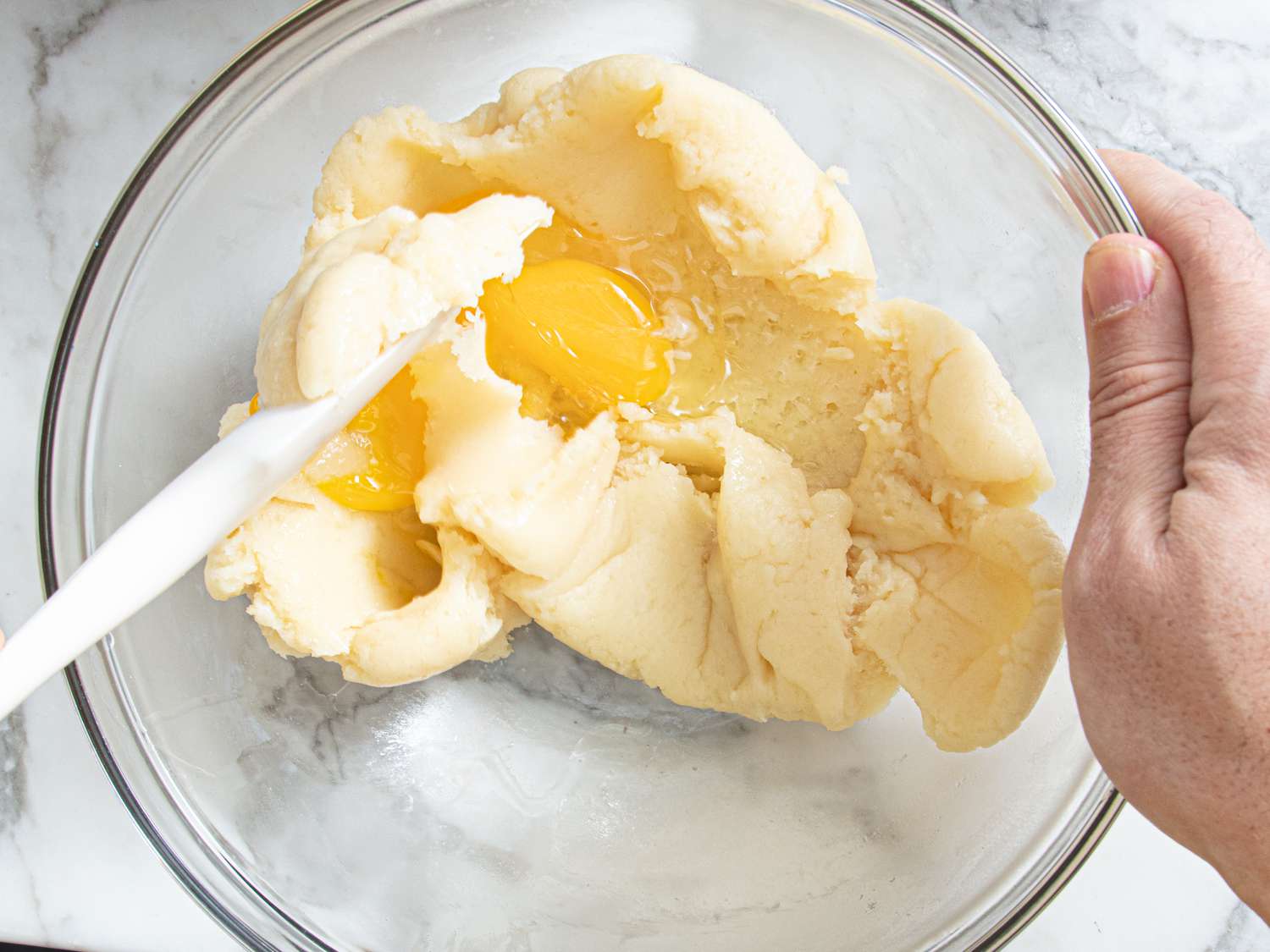 Overhead view of adding eggs to dough