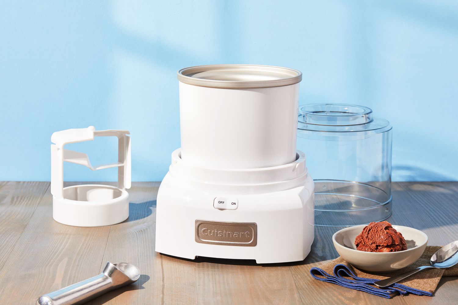 Cuisinart 1.5-Quart Frozen Yogurt, Ice Cream, & Sorbet Maker and its parts displayed on wood surface with bowl of ice cream