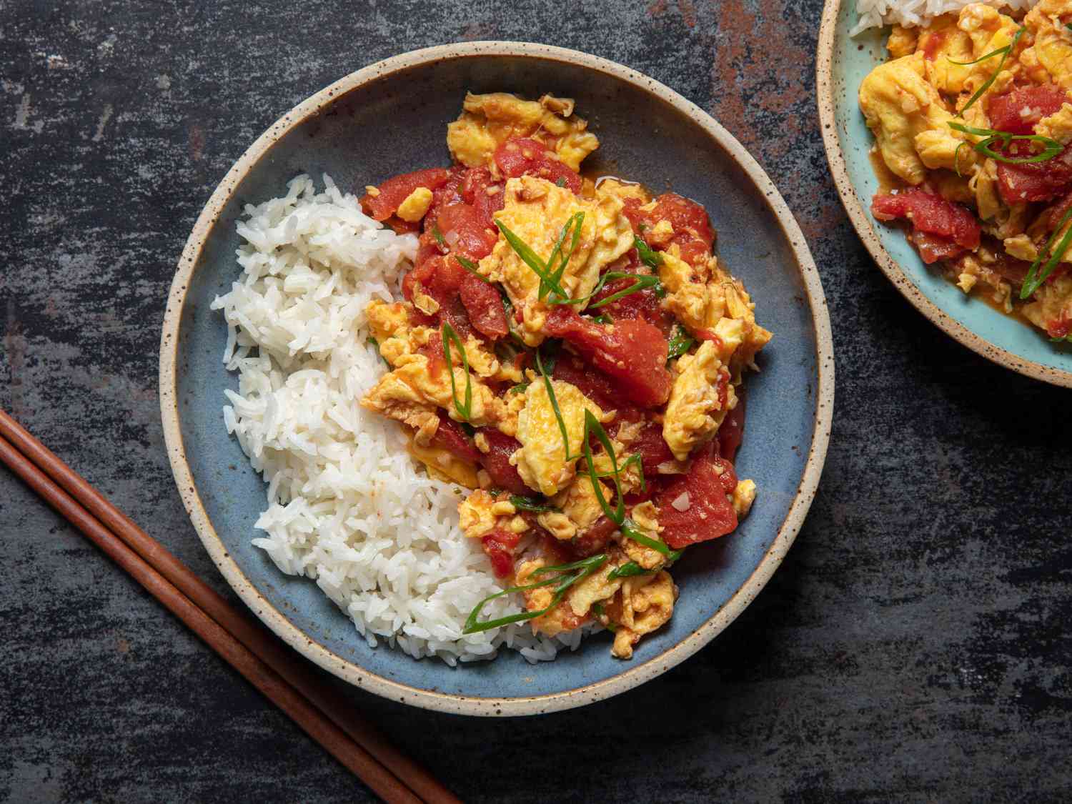 An overhead fully plated tomato and egg dish with chopsticks.
