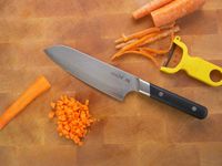 made in damascus santoku on a wooden cutting board with carrots