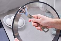 a person holding the folding handle on the le creuset splatter screen