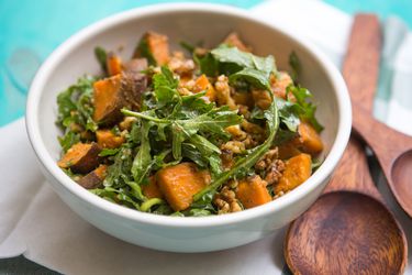Arugula, sweet potato, and walnut dressed with a shoyu-dashi "vinaigrette" in a ceramic bowl with wooden serving spoons on the side