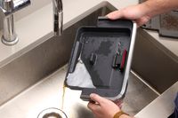 A person washes the parts of the Breville The Barista Pro Espresso Machine in a sink