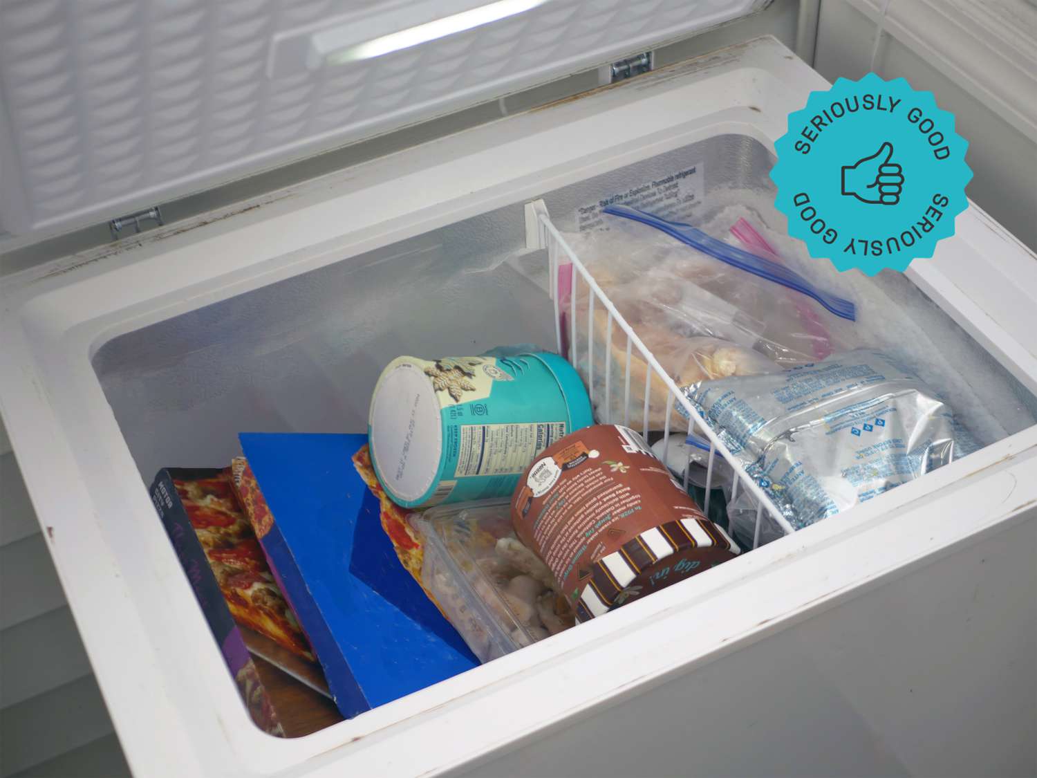 a chest freezer with the lid open revealing pizza boxes, ice cream, and frozen shrimp