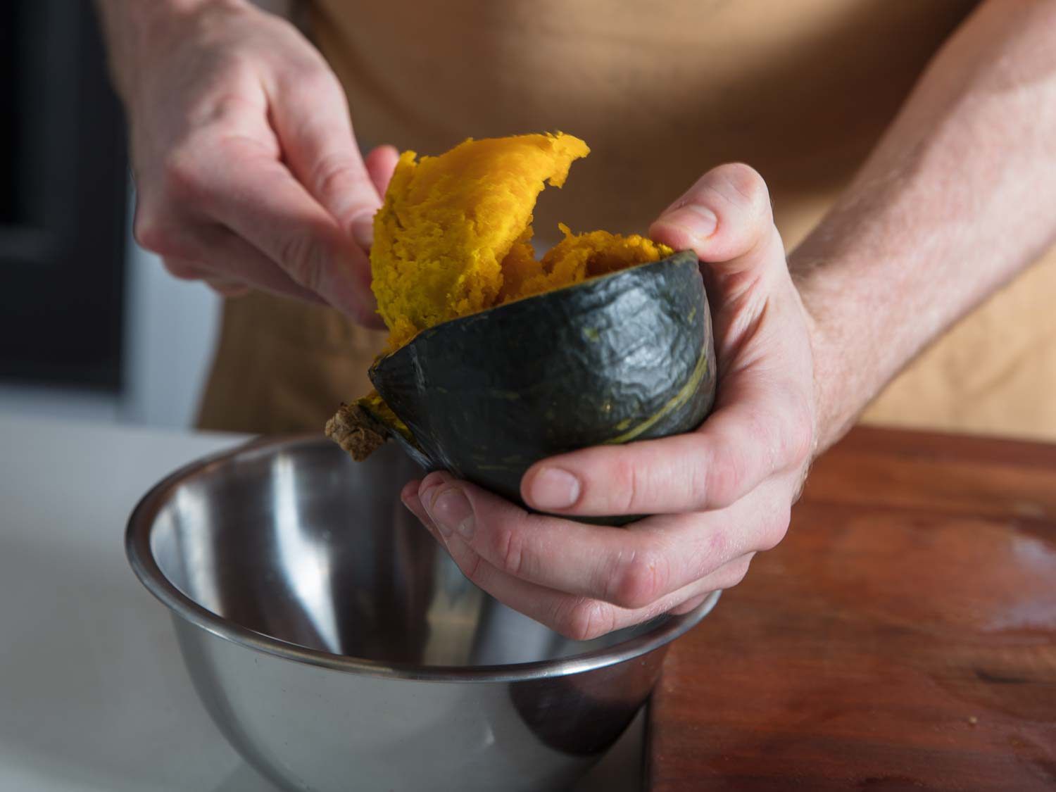 Scooping roasted kabocha squash flesh from skin.