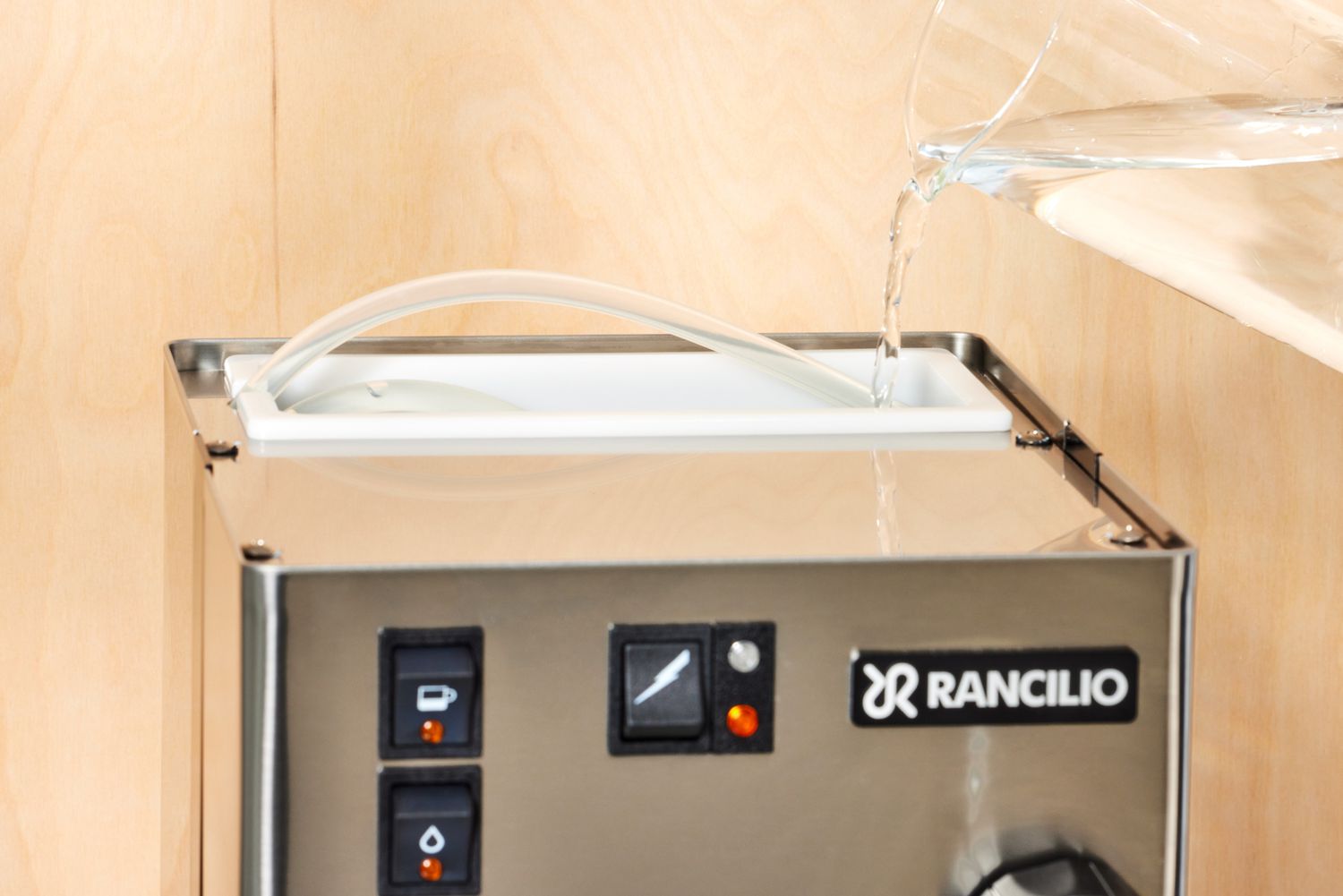 Close up of a person pouring in water to the Rancilio Silvia Espresso Machine