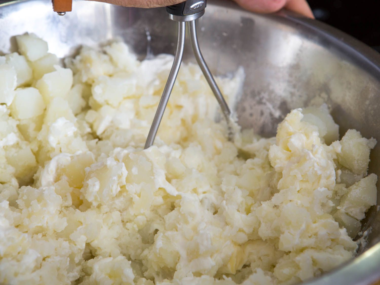 Breaking up cooked potatoes with masher.