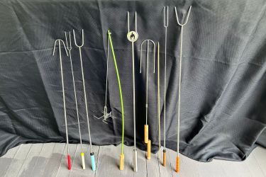 Numerous marshmallow roasting sticks side-by-side.