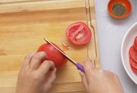 a person slicing a tomato