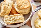 A bowl and plate containing freshly baked buttermilk biscuits