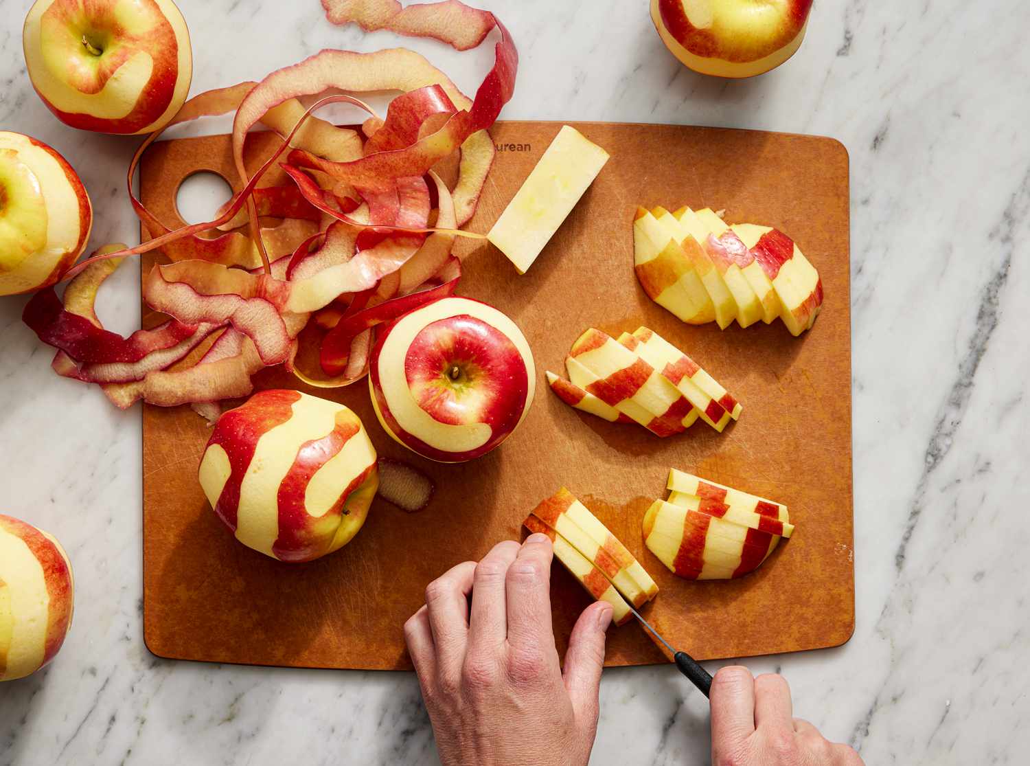 Overhead view of apples being chopped and spiral peeled