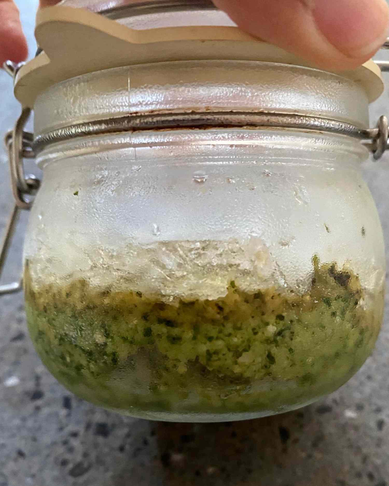 Opened jar containing homemade pesto showing separation of the layers